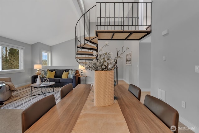 dining room with carpet floors, a towering ceiling, stairway, and baseboards