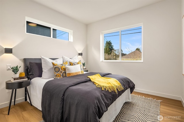 bedroom with multiple windows, baseboards, and wood finished floors