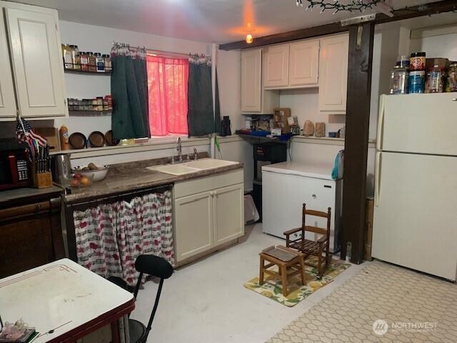 2817 232nd Ln, Ocean Park, WA 98640 - kitchen with freestanding refrigerator, a sink, and white cabinets