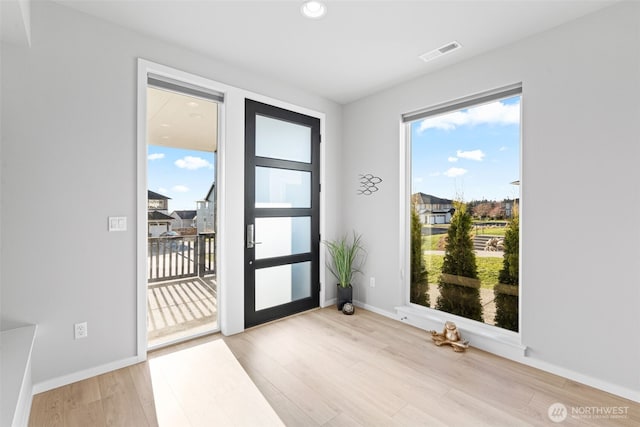 doorway featuring light wood finished floors, visible vents, and baseboards