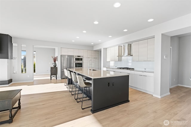 kitchen with white cabinets, modern cabinets, appliances with stainless steel finishes, a breakfast bar, and a sink