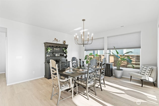 dining area featuring a chandelier, visible vents, baseboards, and wood finished floors