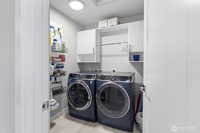 clothes washing area with separate washer and dryer and cabinet space