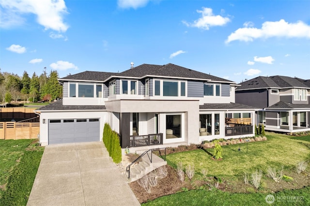 back of property with a garage, driveway, a balcony, fence, and a yard