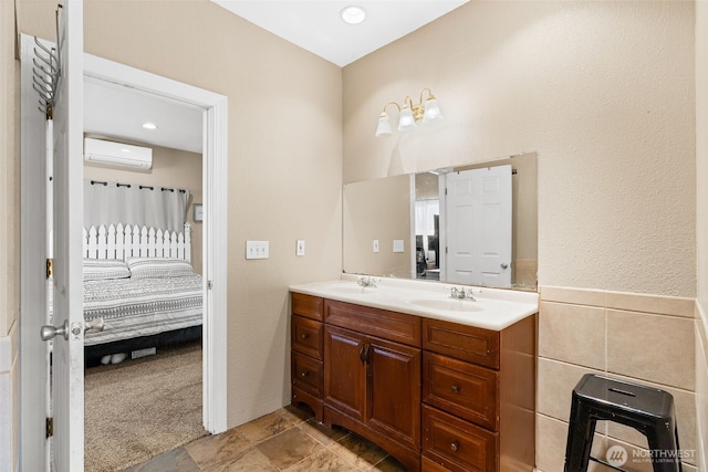 bathroom featuring double vanity, tile walls, ensuite bathroom, an AC wall unit, and a sink