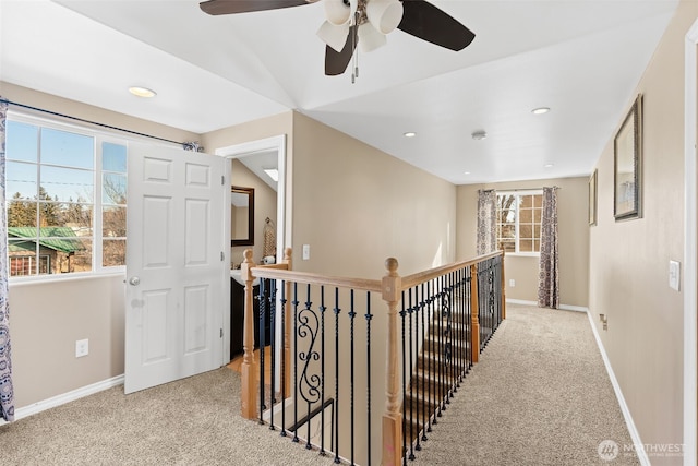 corridor featuring baseboards, plenty of natural light, an upstairs landing, and light colored carpet