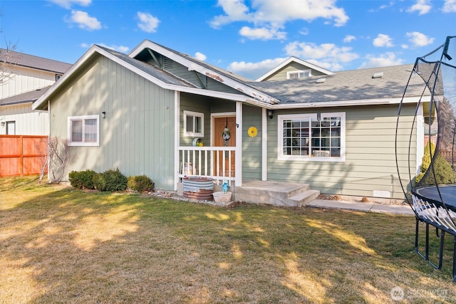 view of front of house featuring a trampoline, a front yard, roof with shingles, and fence