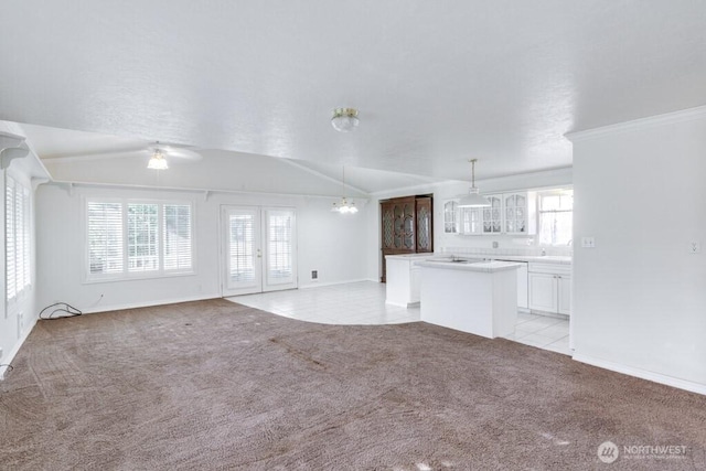 unfurnished living room with lofted ceiling, light tile patterned flooring, light colored carpet, french doors, and an inviting chandelier