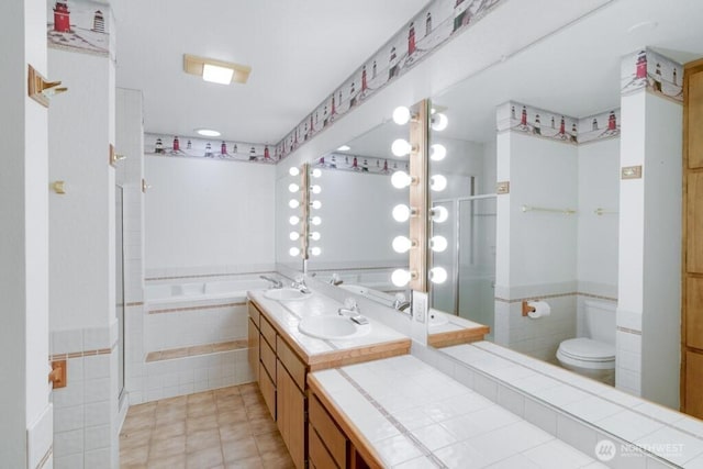 bathroom with a sink, a garden tub, toilet, and a shower stall