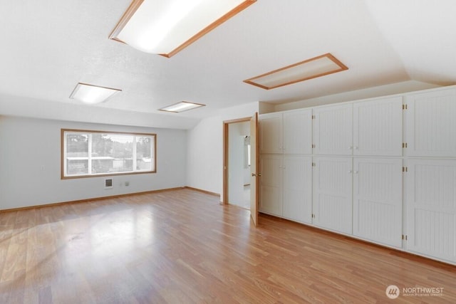 interior space with lofted ceiling, light wood finished floors, and baseboards