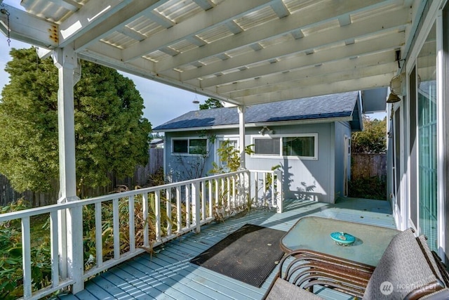 wooden terrace featuring an outbuilding and fence