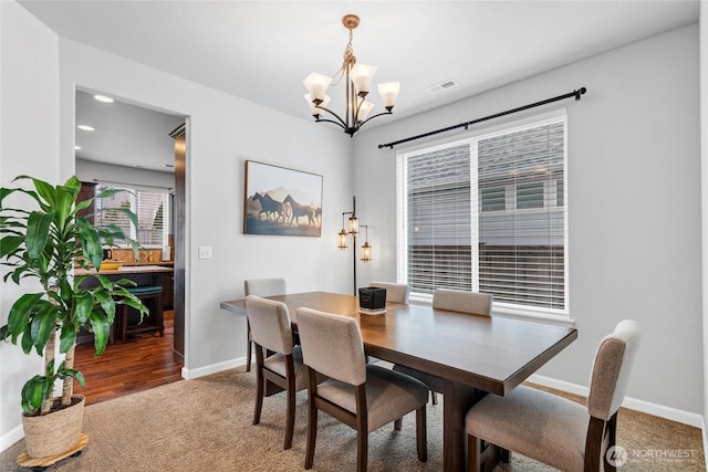 dining area with carpet, visible vents, a chandelier, and baseboards