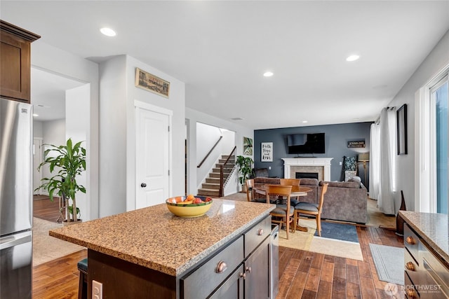 kitchen with recessed lighting, dark wood-style flooring, a fireplace, freestanding refrigerator, and a center island