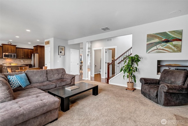 carpeted living area with recessed lighting, visible vents, stairway, and baseboards