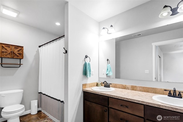 full bathroom featuring visible vents, a sink, toilet, and double vanity