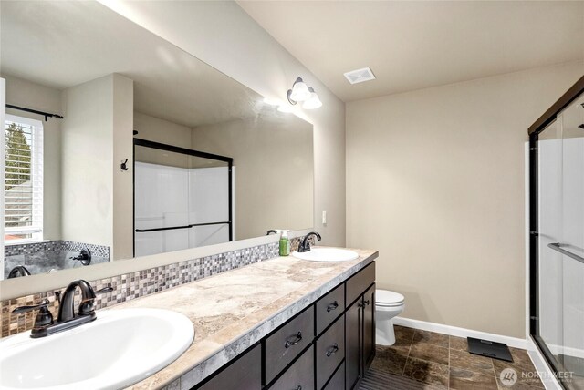 bathroom featuring toilet, a shower stall, visible vents, and a sink