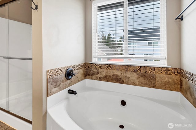 bathroom featuring a stall shower and a bath