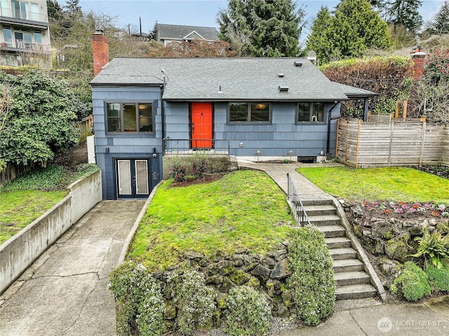 view of front of home featuring a front lawn, fence, roof with shingles, and a chimney