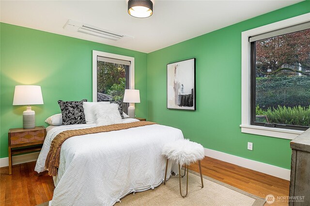 bedroom featuring visible vents, baseboards, and wood finished floors