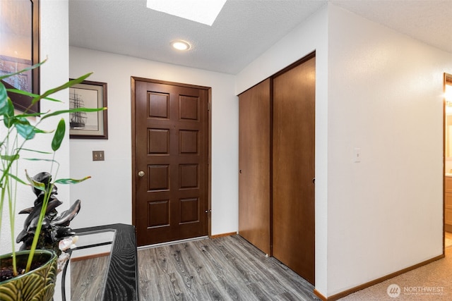 entrance foyer with a skylight, light wood-style flooring, baseboards, and a textured ceiling