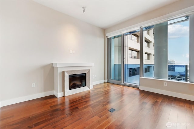 unfurnished living room featuring wood finished floors, a high end fireplace, and baseboards