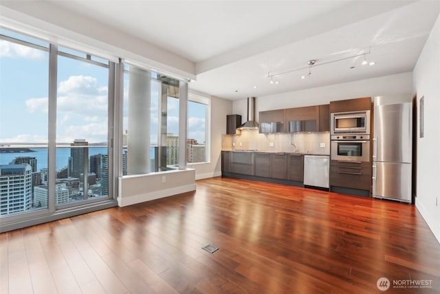 kitchen with wall chimney exhaust hood, modern cabinets, stainless steel appliances, and dark wood finished floors