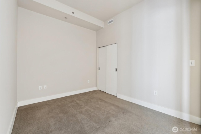 carpeted spare room with visible vents and baseboards