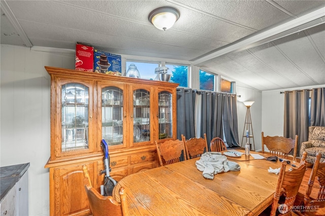 dining space featuring vaulted ceiling with beams