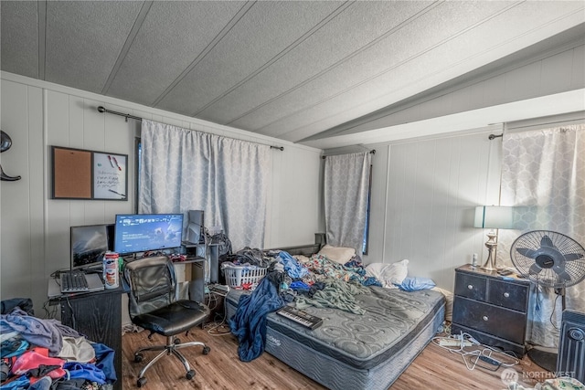 bedroom featuring lofted ceiling, a textured ceiling, and wood finished floors