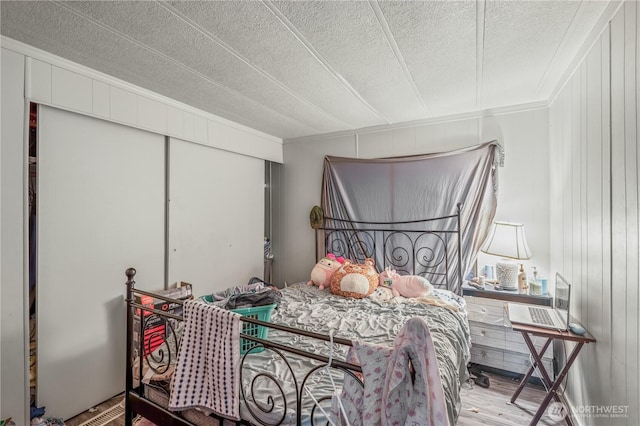 bedroom featuring a textured ceiling, wood finished floors, a closet, and ornamental molding