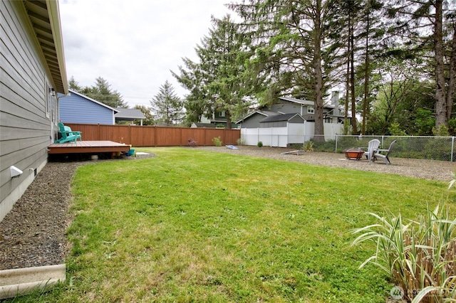 view of yard featuring an outdoor fire pit, a fenced backyard, and a wooden deck