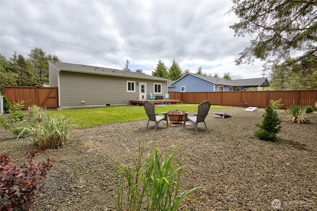 rear view of property with an outdoor fire pit, crawl space, fence, and a lawn