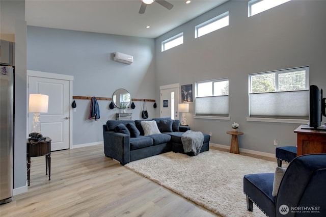 living area featuring baseboards, an AC wall unit, recessed lighting, and light wood-style floors