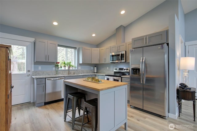 kitchen with a sink, stainless steel appliances, gray cabinets, and wooden counters