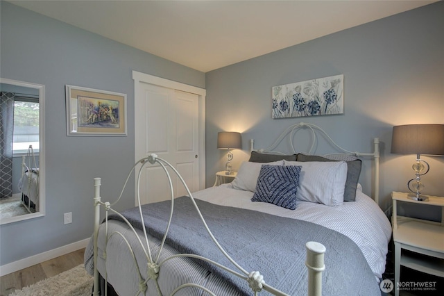 bedroom with a closet, wood finished floors, and baseboards