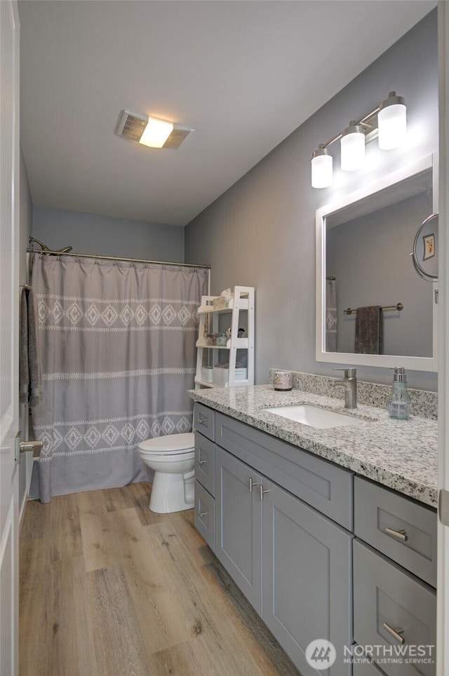 bathroom featuring toilet, a shower with curtain, wood finished floors, and vanity