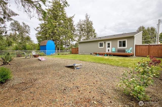 rear view of property featuring a fenced backyard, a yard, a deck, and an outdoor structure