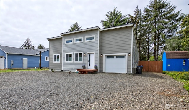 view of front of property featuring an outbuilding, gravel driveway, a storage unit, fence, and a garage