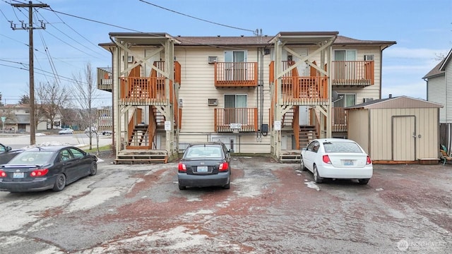 townhome / multi-family property with an outdoor structure, a storage shed, and stairs