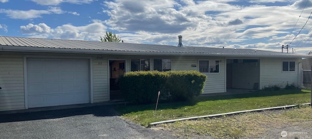 single story home with an attached garage, metal roof, and a front yard