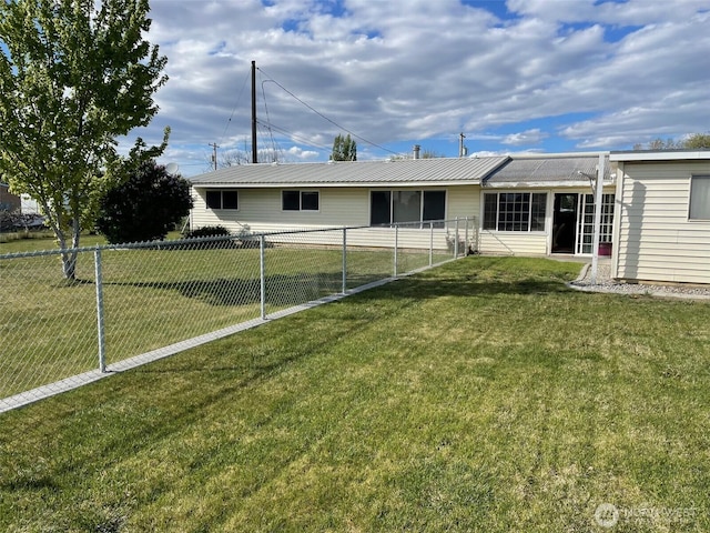 rear view of property featuring metal roof, a yard, and fence