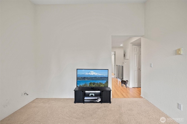 living area with a high ceiling and carpet flooring