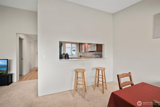 dining space with light colored carpet and a towering ceiling