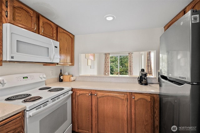 kitchen with light countertops, white appliances, and brown cabinets