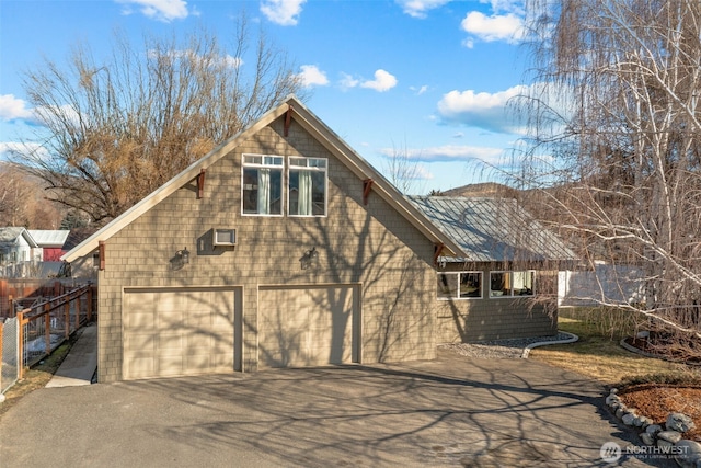 exterior space with aphalt driveway, an attached garage, and fence