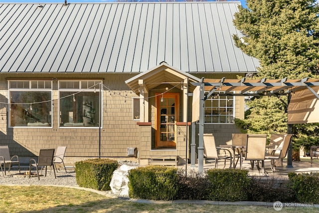 property entrance featuring metal roof, a patio, a standing seam roof, and a pergola