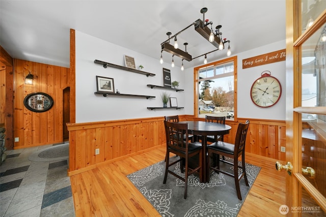 dining space featuring wood finished floors, wood walls, and wainscoting