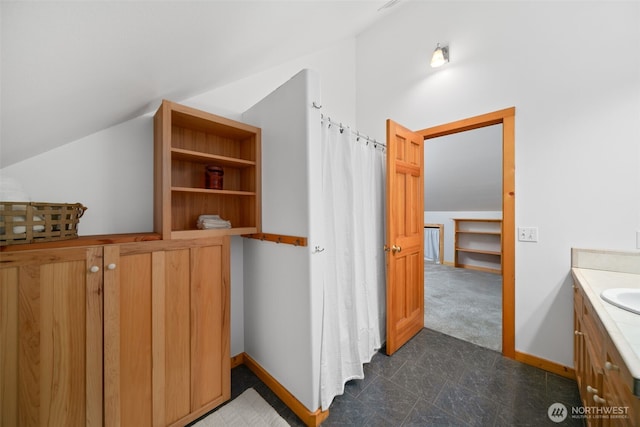 full bathroom featuring vanity, lofted ceiling, and baseboards