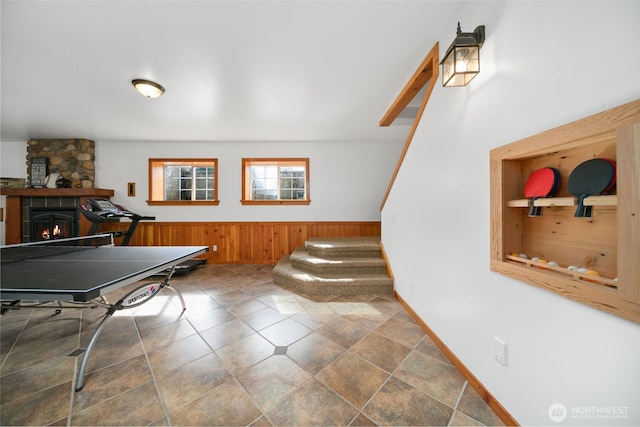 rec room with a fireplace, wainscoting, and wood walls