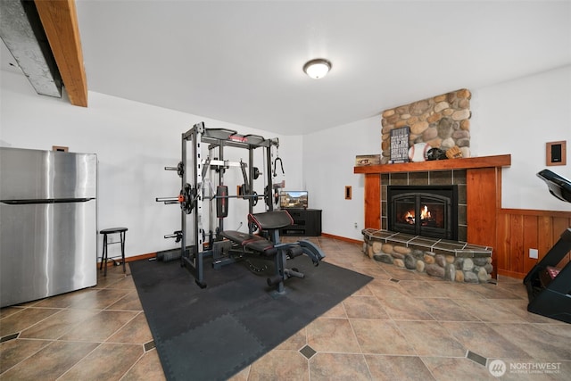 workout room with a stone fireplace and tile patterned floors